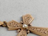 an image of a gold cross with a pearl in the center