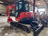 a small red excavator parked in a warehouse
