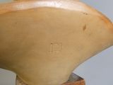 une sculpture représentant une tête d'homme posée sur un socle en bois