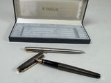 a black pen and a silver pen sitting on a table
