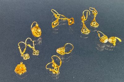 Plusieurs paires de boucles d'oreilles en or sont exposées sur un fond noir