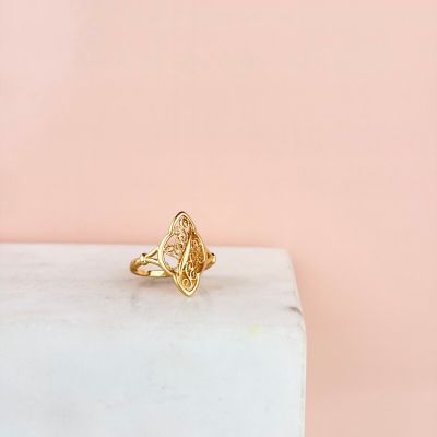 une bague en or posée sur un bloc de marbre, sur fond rose