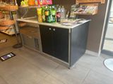a counter with bottles of beer on it and a phone on the floor