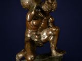 bronze statue of a boy holding a ball on a wooden stand