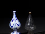 two glass vases sitting on top of a table next to each other