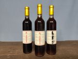 three bottles of wine sitting on a wooden table