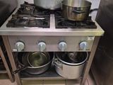 des casseroles et des poêles sont posées sur une cuisinière en acier inoxydable dans une cuisine professionnelle