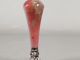 a red vase with a silver base on a table