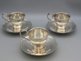 three silverplated cups and saucers on a saucer
