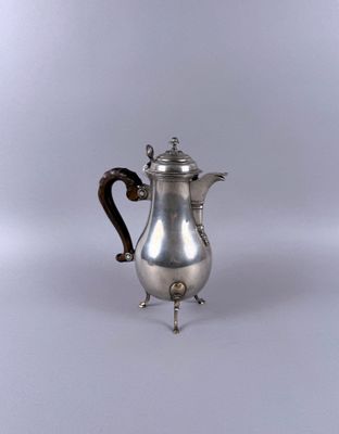 an antique silver coffee pot on a stand on a white background