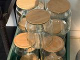 a green crate filled with glass jars and wooden lids