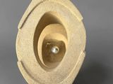 an image of a sculpture made out of concrete with a pearl in the center