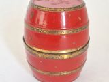 a red barrel with gold stripes sitting on a white surface