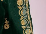 a close up of a green jacket with gold embroidery on it