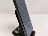 the back of a black cell phone on a stand on a white surface