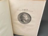 un livre ouvert posé sur une table, à côté d'une pièce de monnaie