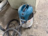 un aspirateur bleu et noir posé par terre à côté d'une poubelle