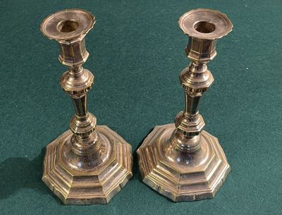 deux bougeoirs en argent posés sur une table verte