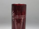 un vase en verre rouge posé sur une surface blanche