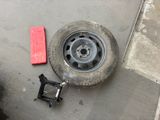 a tire that is sitting on the ground next to a red piece of luggage