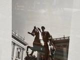 a black and white photo of a man on a horse in front of a building