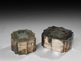 deux boîtes argentées posées l'une à côté de l'autre sur une surface blanche
