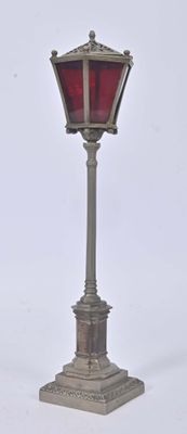 a silver lamp post with a red glass shade on it