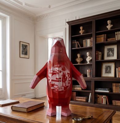 sculpture représentant un manchot rouge assis sur une table en bois dans un salon