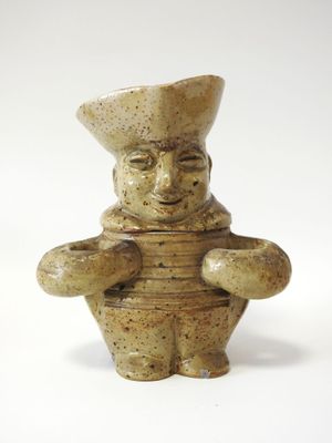 une petite figurine en céramique représentant un chef tenant une casserole