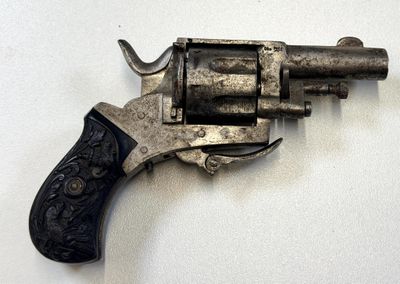 un pistolet posé sur une surface blanche, avec une crosse noire