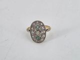 a close up of a diamond and emerald ring on a white surface