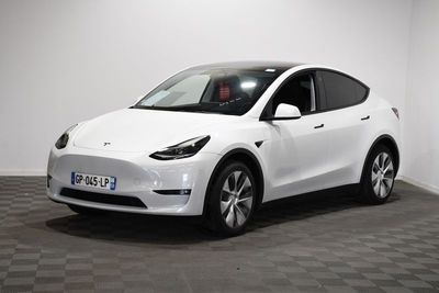 un SUV Tesla blanc garé dans une pièce au sol en damier