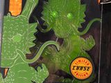a green dragon toy in a plastic package on a table