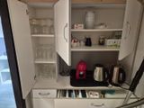 une petite cuisine avec une cafetière et des verres à vin posés sur le plan de travail