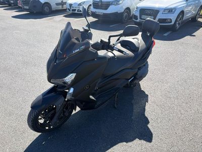 une moto noire garée sur un parking, avec d'autres voitures en arrière-plan