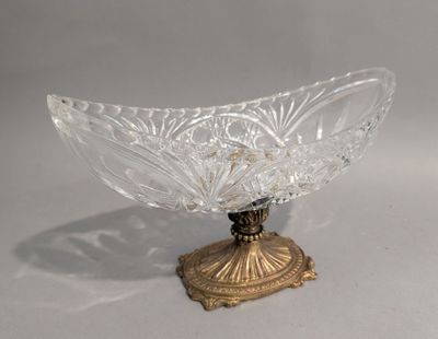 un bol en verre posé sur un socle doré, sur une surface blanche