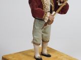 une figurine représentant un garçon tenant un bâton, posée sur une boîte