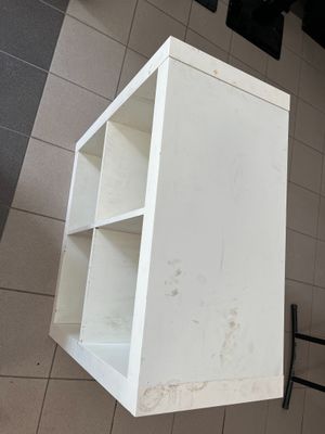 a white shelf with a black chair in the corner