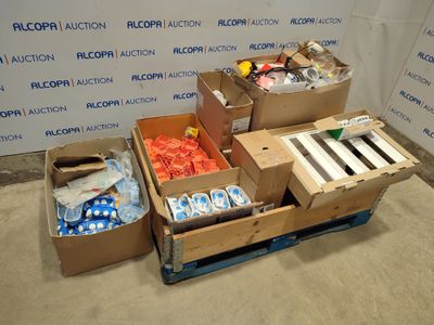 Plusieurs cartons contenant des articles divers sont posés sur une palette devant un mur.