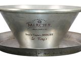 a large metal bowl with a handle on a plate