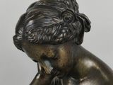 an antique bronze statue of a woman sitting on a rock