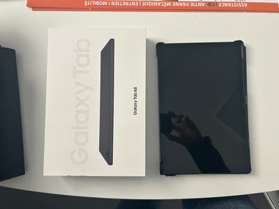 une tablette noire posée sur une table, à côté d'une boîte