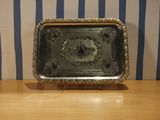 a silver tray on a wooden table with a striped wall behind it