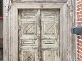 entrée d'un immeuble en briques avec une porte en bois et un mur en briques