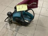 a small corded sander on the floor with a note attached to it