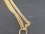 a close up of a gold necklace on a black surface