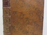 an old book sitting on top of a white surface with writing on it