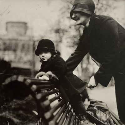 une photo en noir et blanc d'un homme et d'un enfant assis sur un banc dans un parc