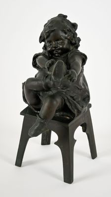 une petite statue représentant un enfant assis sur un tabouret