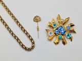 a gold chain with a blue flower brooch and a gold chain with a blue flower brooch